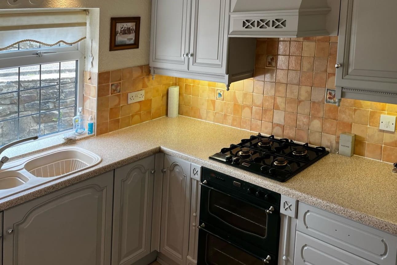 A kitchen resprayed in a pale grey, extractor canopy included