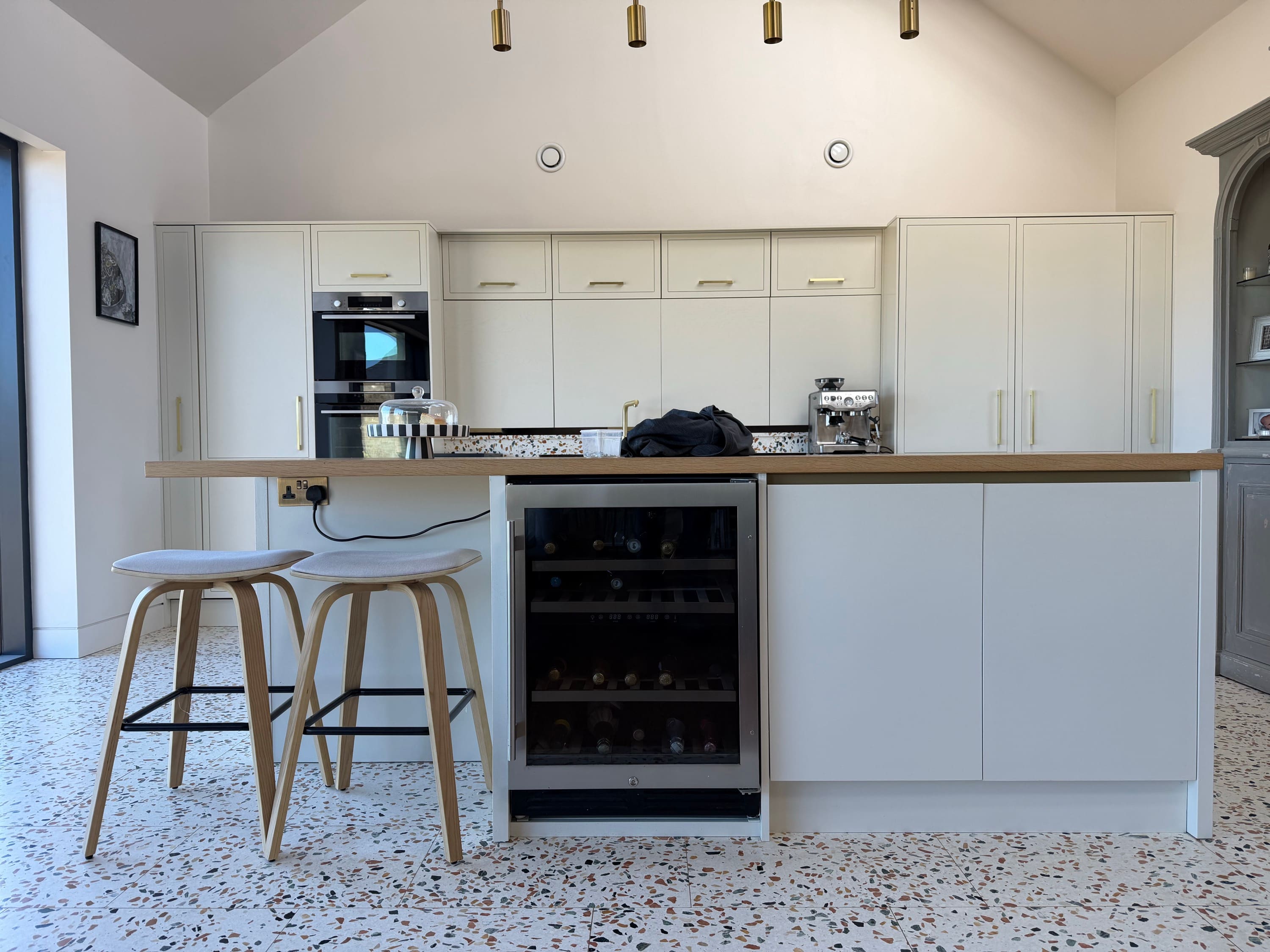 Cream kitchen respray with brass pendant lighting and wine fridge