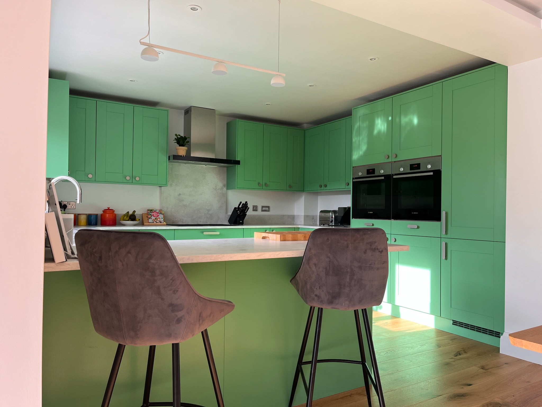 Deep green kitchen units after respraying, with a pale stone worktop