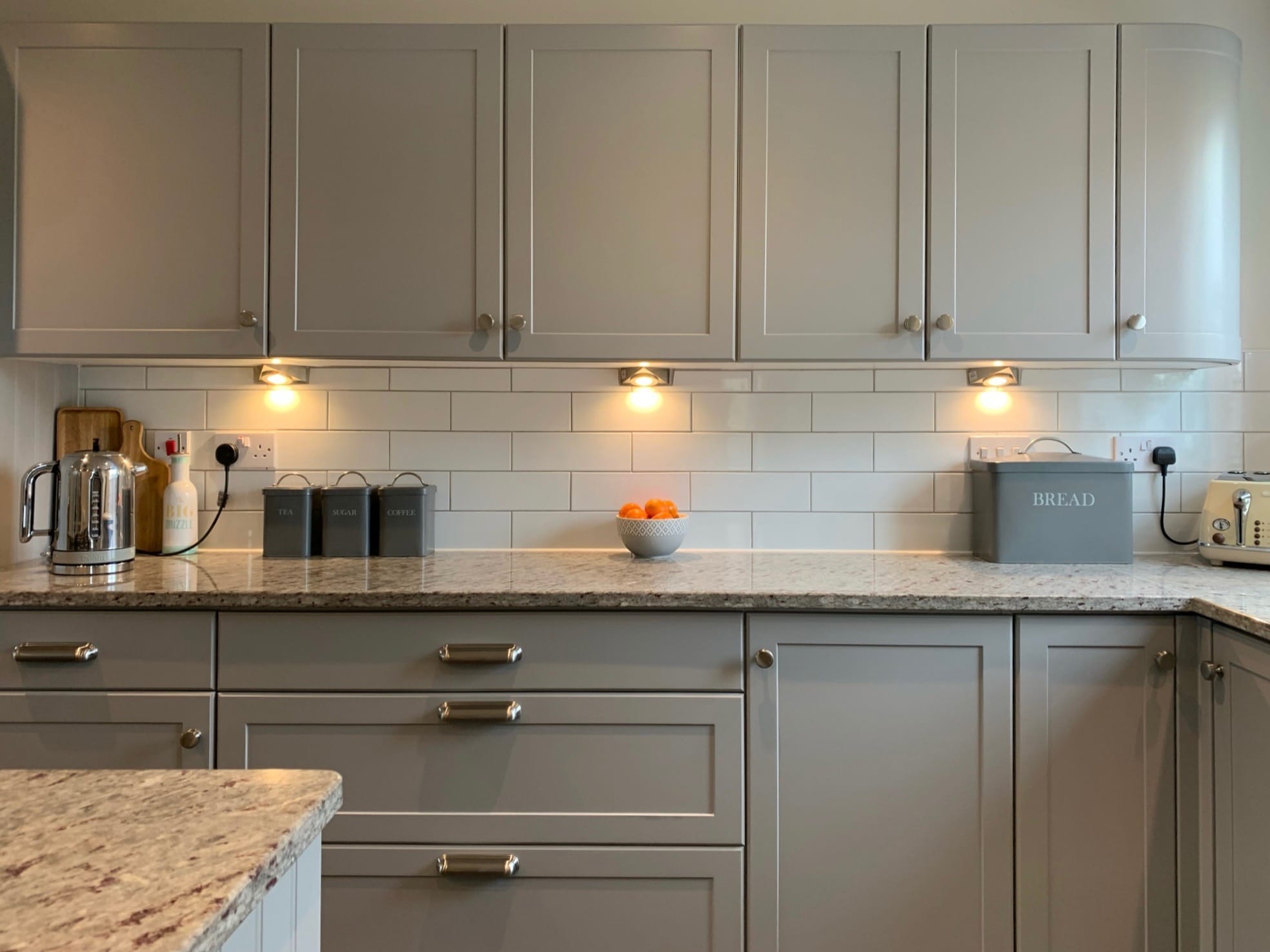 Dove grey kitchen after respraying, with a speckled granite worktop